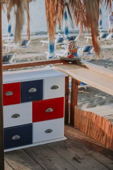 Colorful wooden cabinet at a beachside nipa hut with sandy shore and straw roof decor.