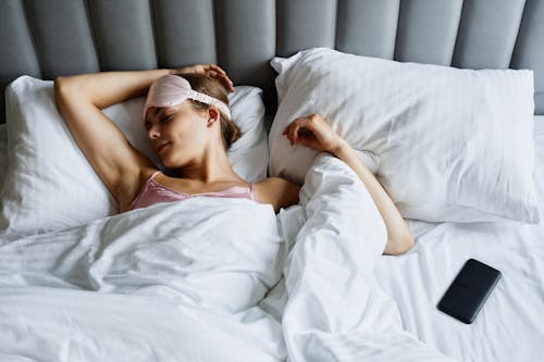Free A Woman with Eye Mask Sleeping in the Bed Stock Photo