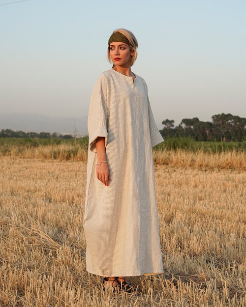 Free Woman in White Long Sleeve Dress Standing on Brown Grass Field Stock Photo