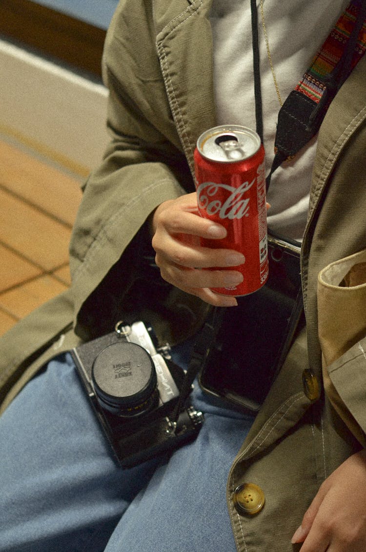 A Person Holding A Can Of Coke