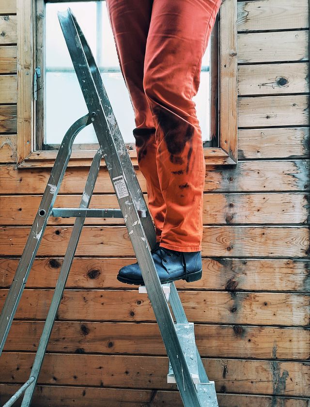 Technician on a ladder working on an exterior wall