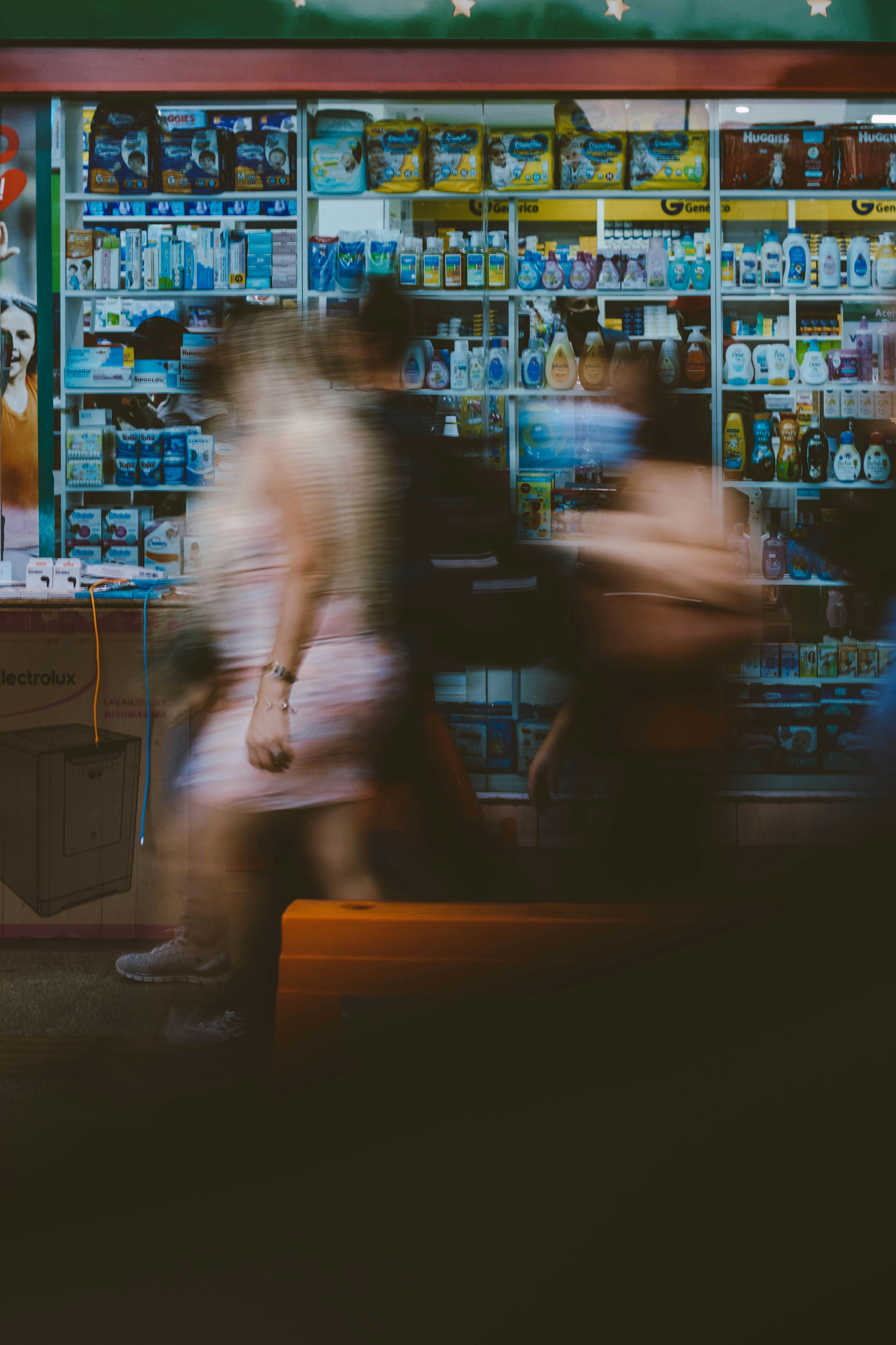 Artistic long exposure capture of people walking past a storefront at night, Brasília, Brazil.