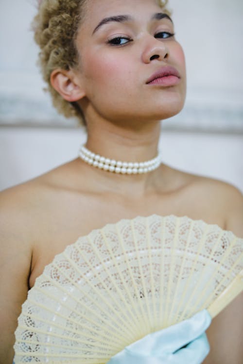 A Woman Holding a Fan while Seriously Looking at Camera