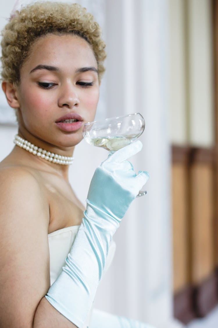 A Woman Wearing A Satin Glove Holding A Wine Glass