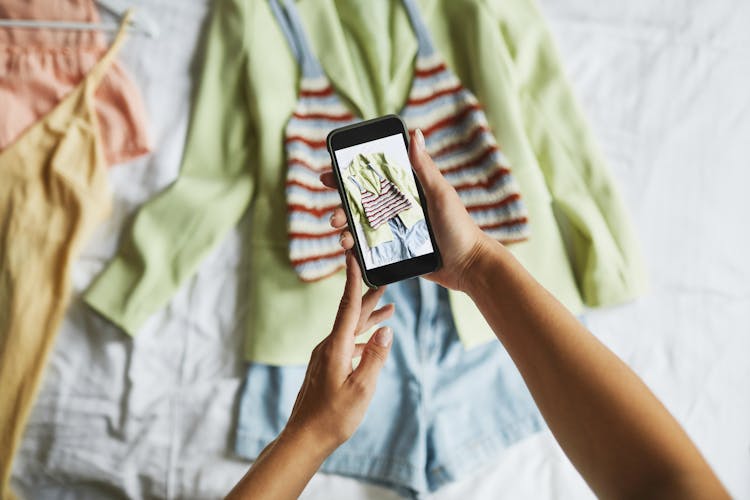 Person Taking Photos Of The Clothes On The Bed 