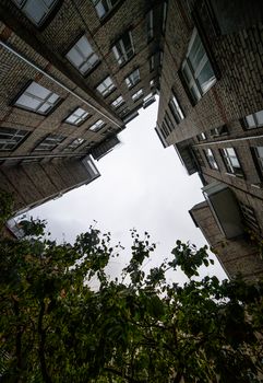 Upward view of brick buildings in Copenhagen with glass windows under a white sky.