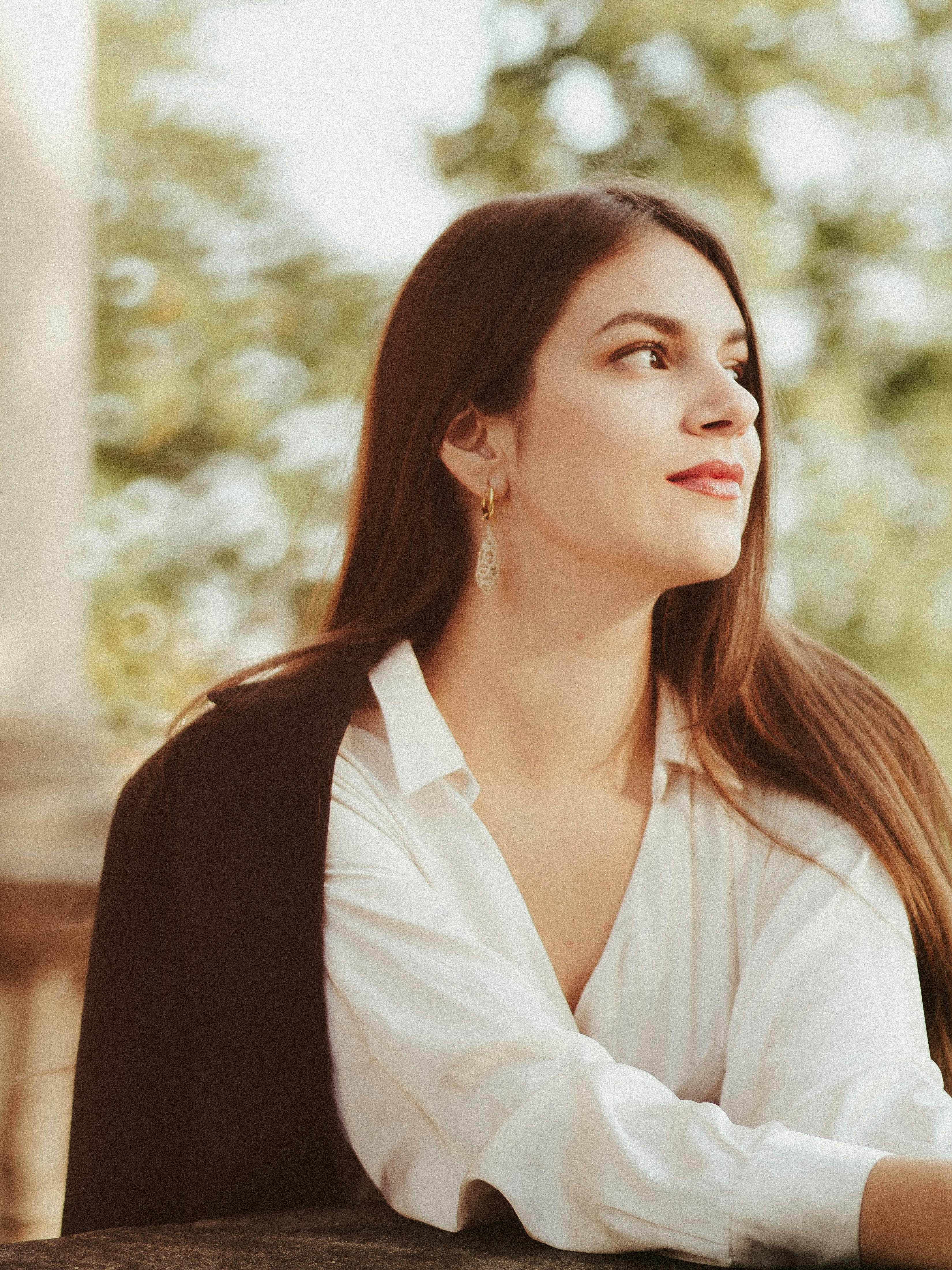 Portrait of a young woman in white enjoying a sunny day outdoors.