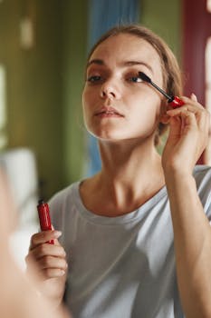 Close-up of a woman applying mascara indoors, focusing on makeup detail.