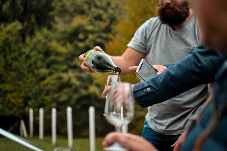 Men Pouring Wine In Glasses Outdoors