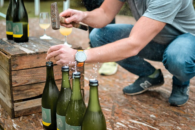 Person Hammering A Nail On Bottles