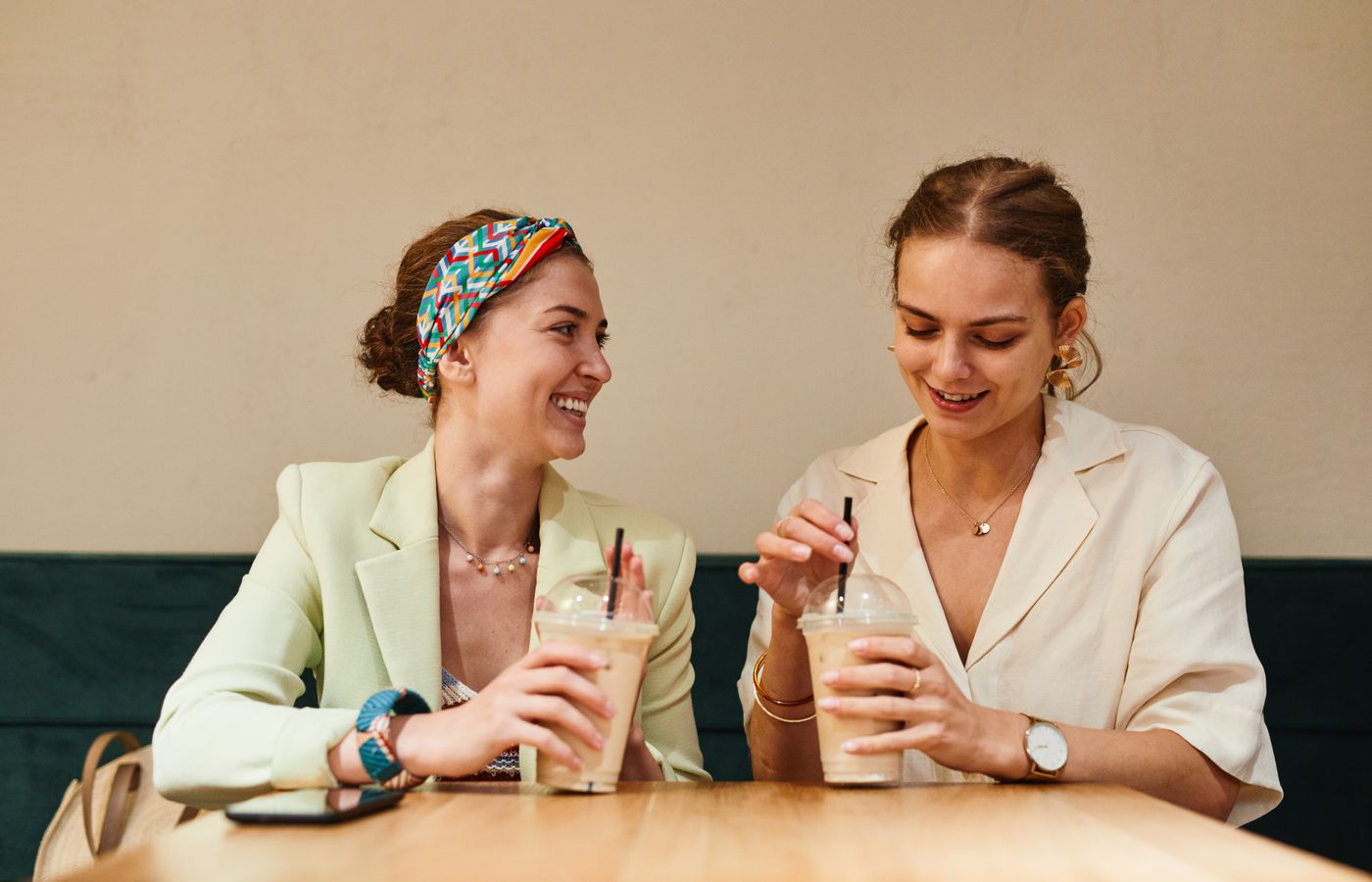 Two young women having a lively conversation over iced coffee at a café.