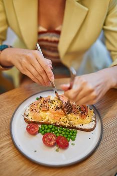 Delicious smoked salmon sandwich with cherry tomatoes and peas on a plate, perfect for lunch.