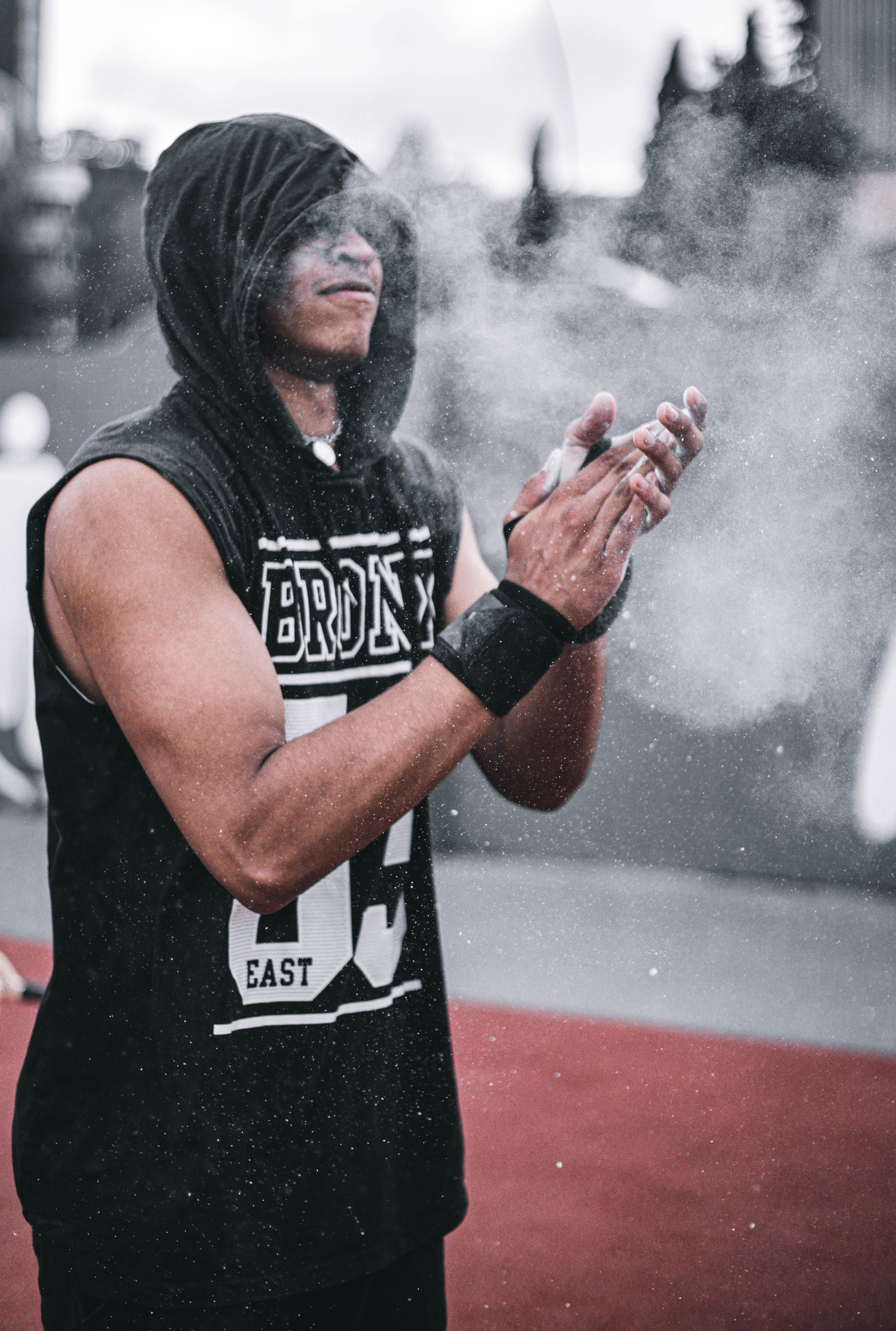 Muscular athlete claps talc powder before exercise in Barcelona outdoor sports venue.
