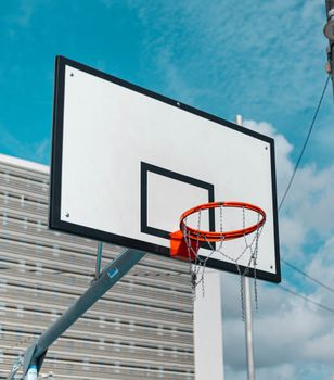 Basketball hoop with metal net outdoors in Barcelona, Spain, under bright blue sky.