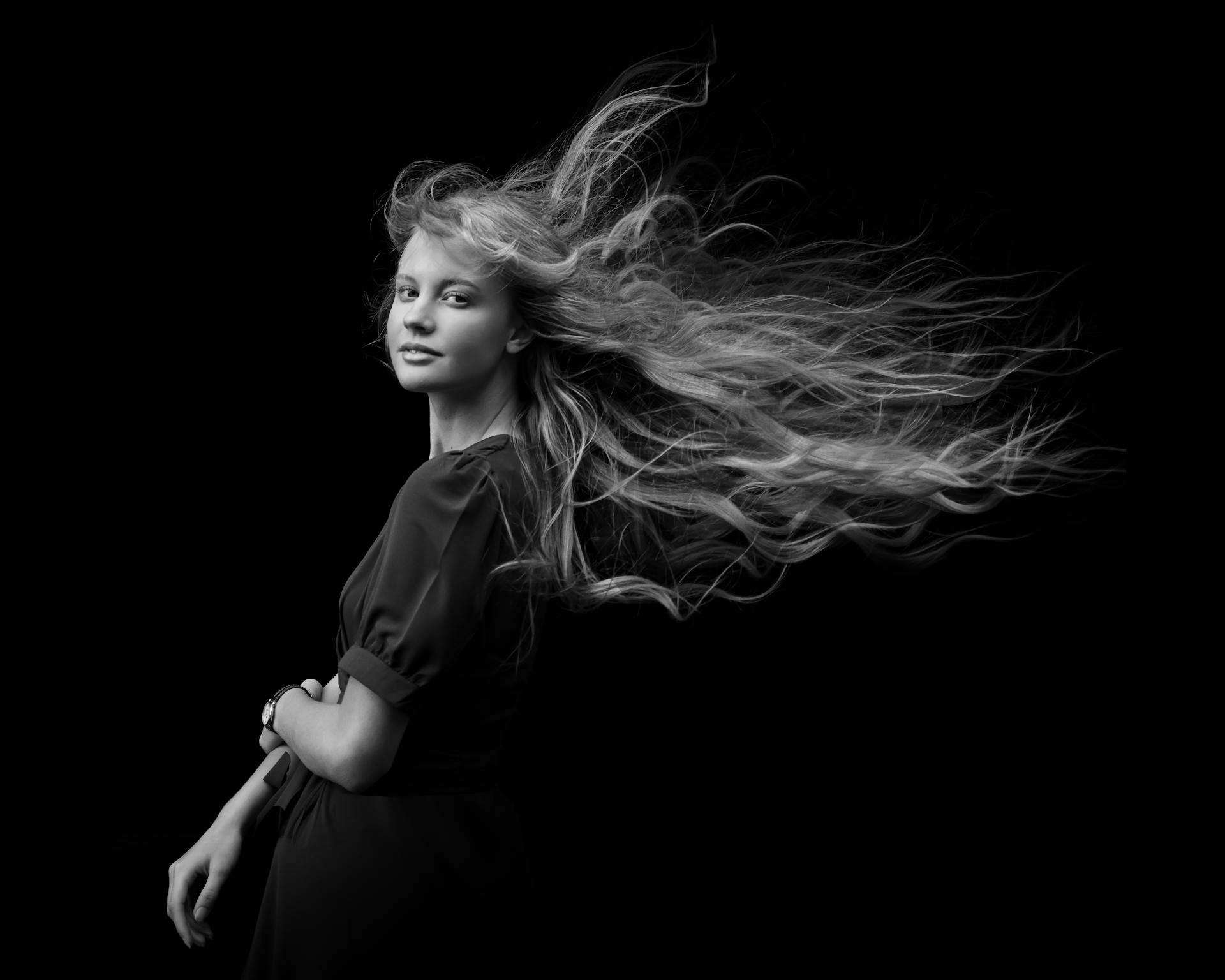 Striking black and white studio portrait of a woman with long hair flowing elegantly.