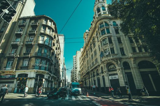 A vibrant city street with historic buildings, cars, and pedestrians.