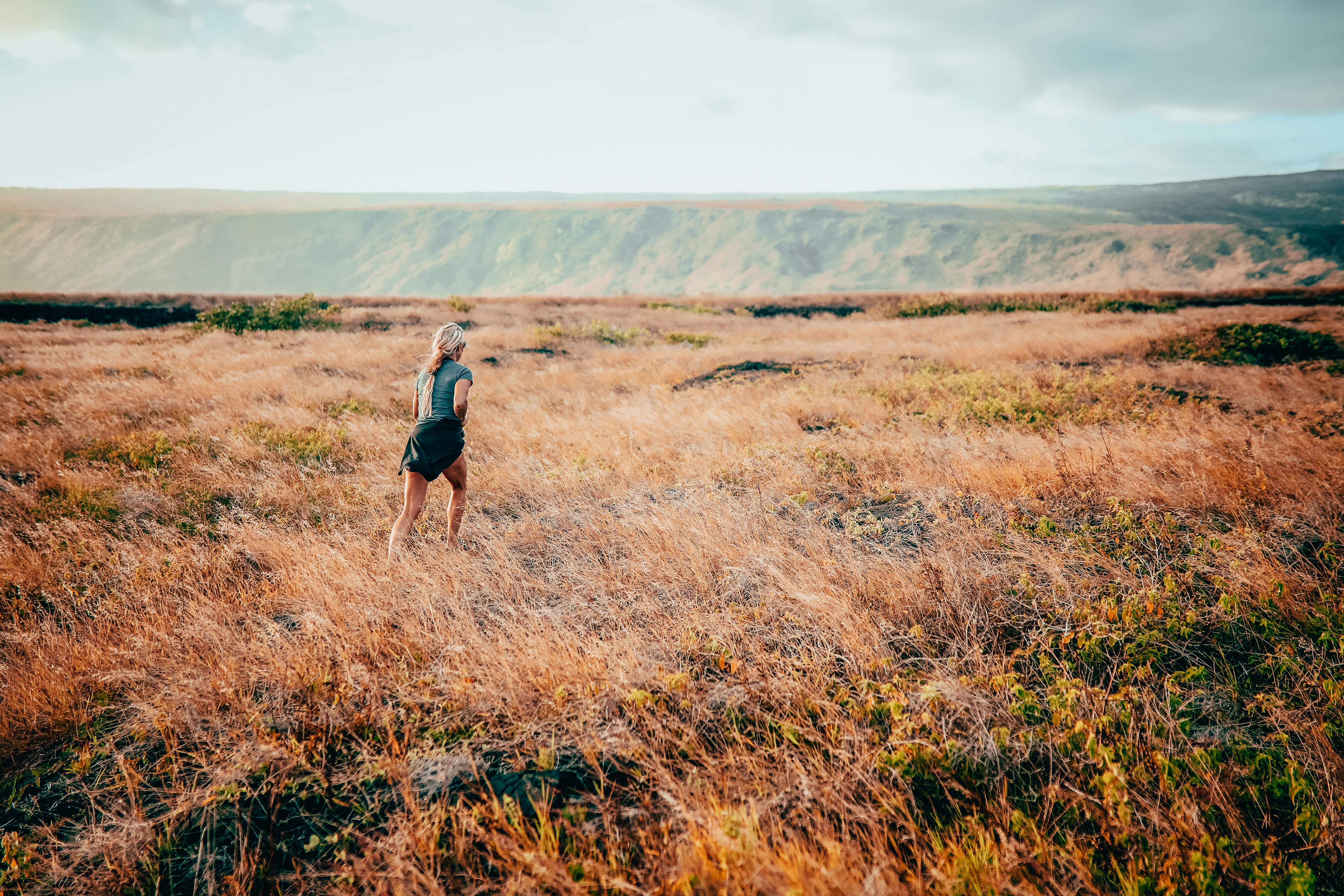 A woman runs freely through expansive grasslands in Hawaii, embracing nature and adventure.