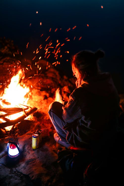 A Woman Sitting in Front of a Bonfire