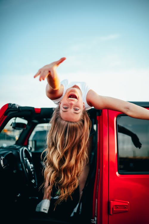 Girl laying on car roof reaching out smiling