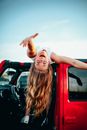 Girl laying on car roof reaching out smiling