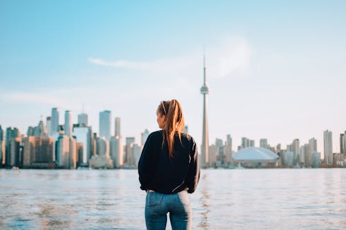 Woman in Black Jacket and Blue Denim Jeans Standing on Dock