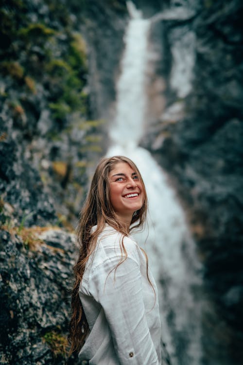 Woman in White Long Sleeves Standing Near the Waterfalls