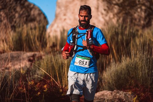 Free A bearded man participates in a trail running race through rugged outdoor terrain, showing determination. Stock Photo