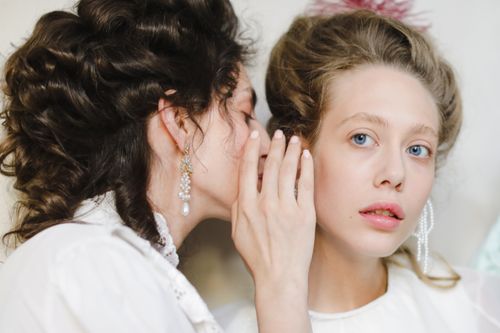 Free Two women dressed in 19th century fashion share a secret, showcasing elegance and friendship. Stock Photo