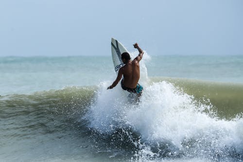  A Man in Blue Shorts Surfing on the Sea