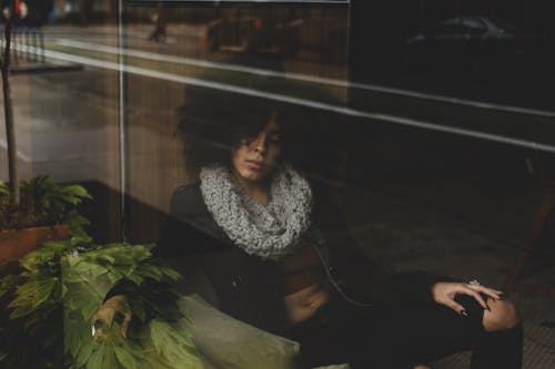 Free A Woman Sitting Beside the Glass Window Stock Photo