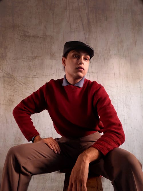 A Man in Red Long Sleeve Shirt and Brown Pants Sitting on Brown Wooden Chair