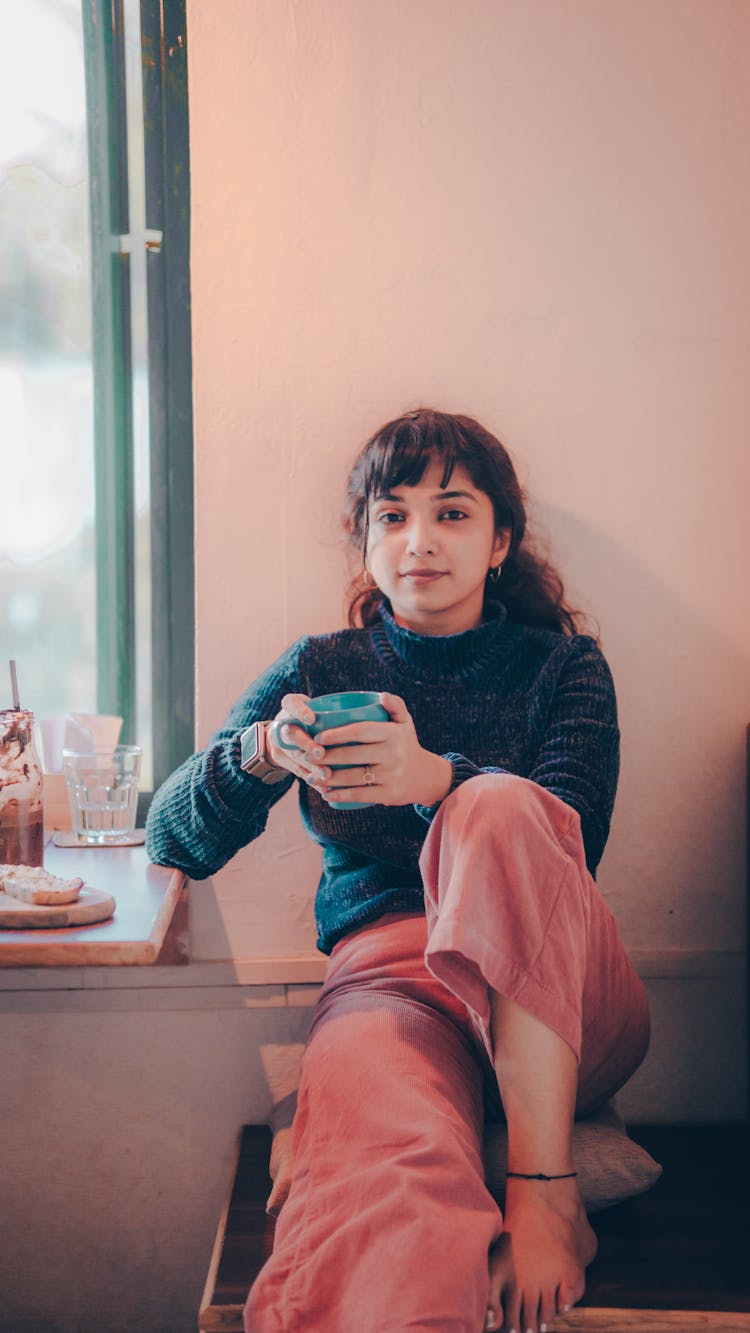 Woman Sitting In Kitchen Drinking Tea