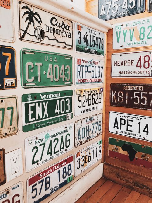 Free Colorful vintage license plates from various US states displayed on a wall. Stock Photo