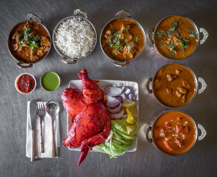 Overhead spread of curries, rice and grilled dishes — photo by Alberta Studios on Pexels