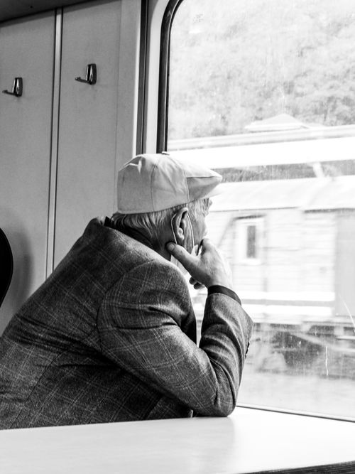 Free Elderly man gazing out of a train window, captured in monochrome, reflecting travel and nostalgia. Stock Photo