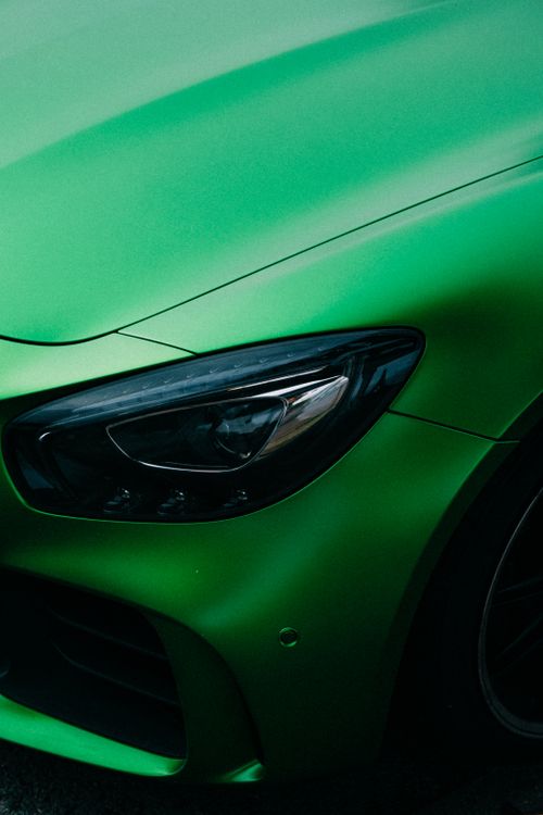 Free Close-up of a luxury sports car's green exterior with a focus on the sleek headlight design. Stock Photo