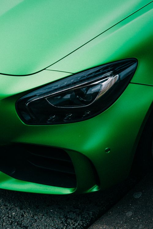 Free Close-up of a sleek green luxury car's headlight with sharp details. Stock Photo