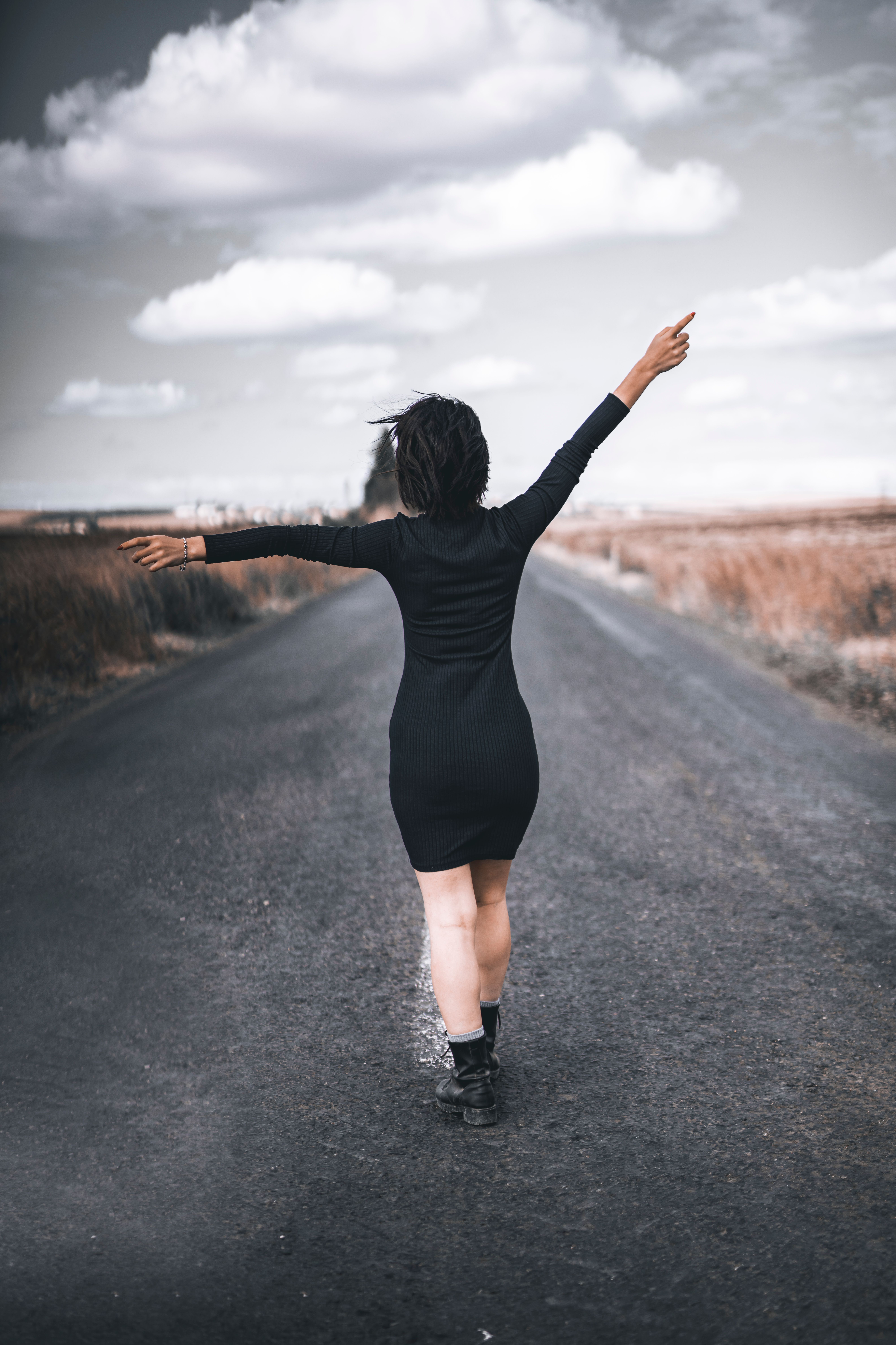 Back View of a Woman in a Black Dress Standing on a Road · Free Stock Photo