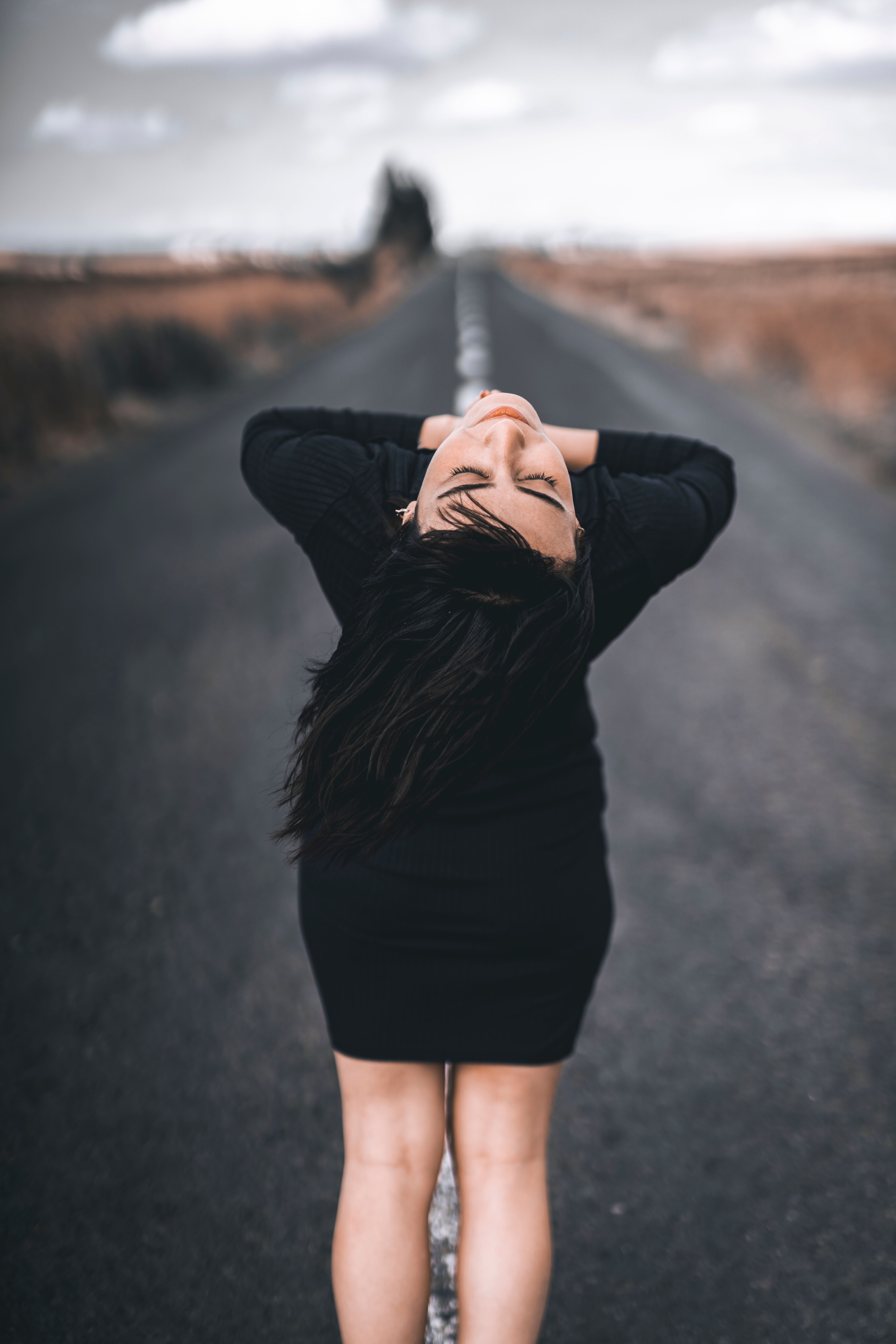 Back View of a Woman in a Black Dress Standing on a Road · Free Stock Photo