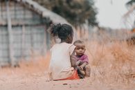 Two children sitting in a rural Madagascar village scene, depicting local life.