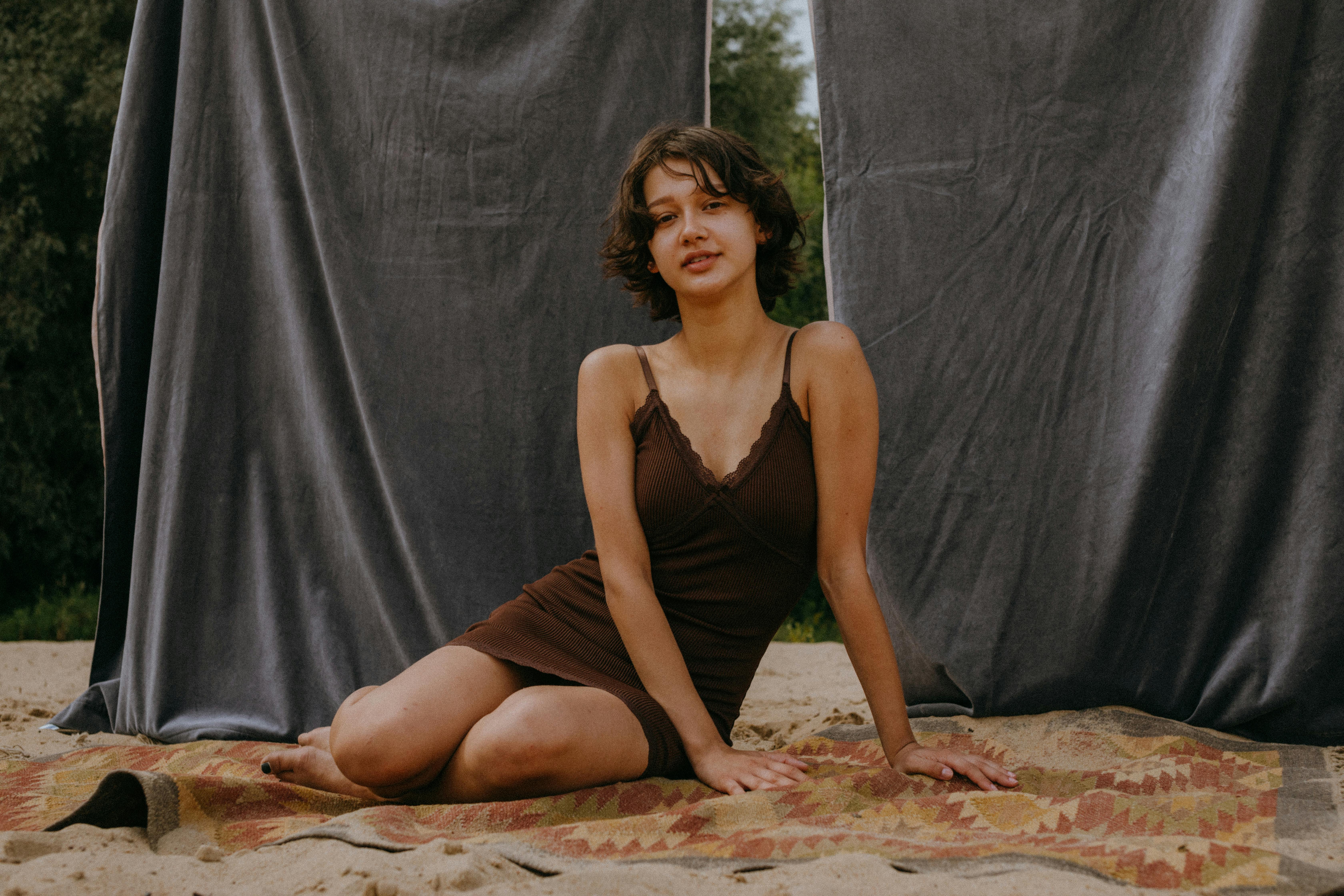 woman in brown spaghetti strap dress sitting on a blanket