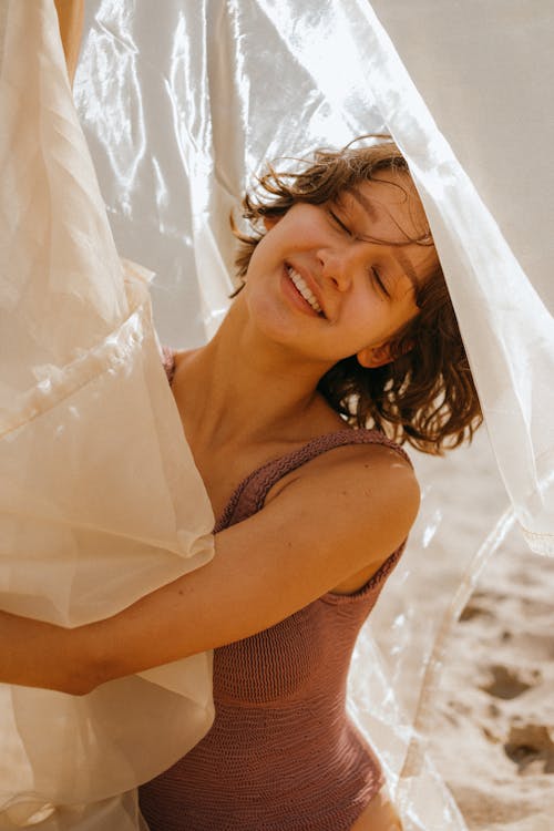 Woman in Bodysuit Holding Sheer Fabrics