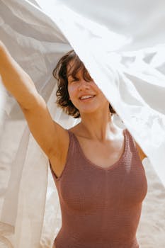Smiling woman in sleeveless shirt with fabric, enjoying sunny day outdoors.