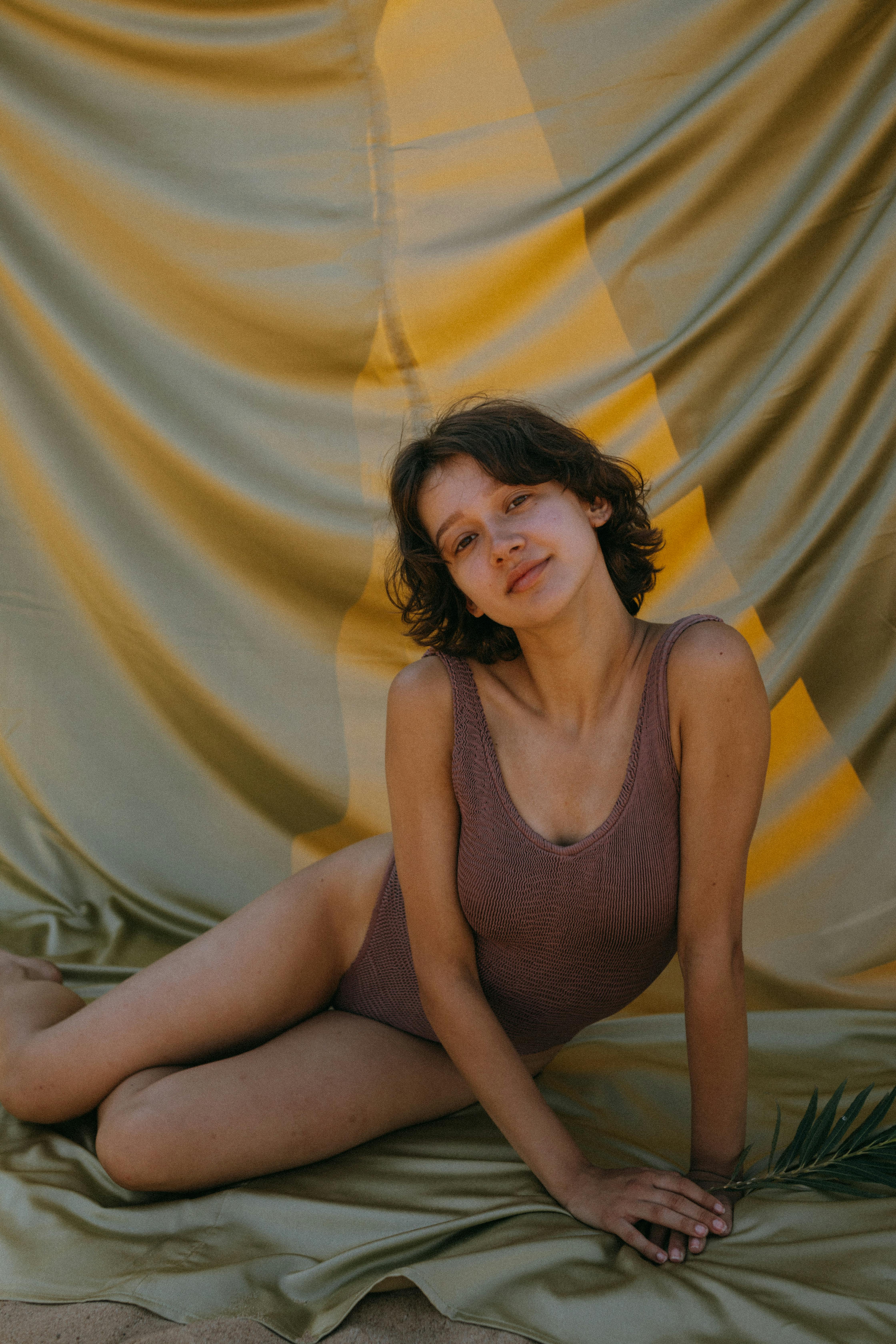 woman wearing swimsuit sitting on satin fabric