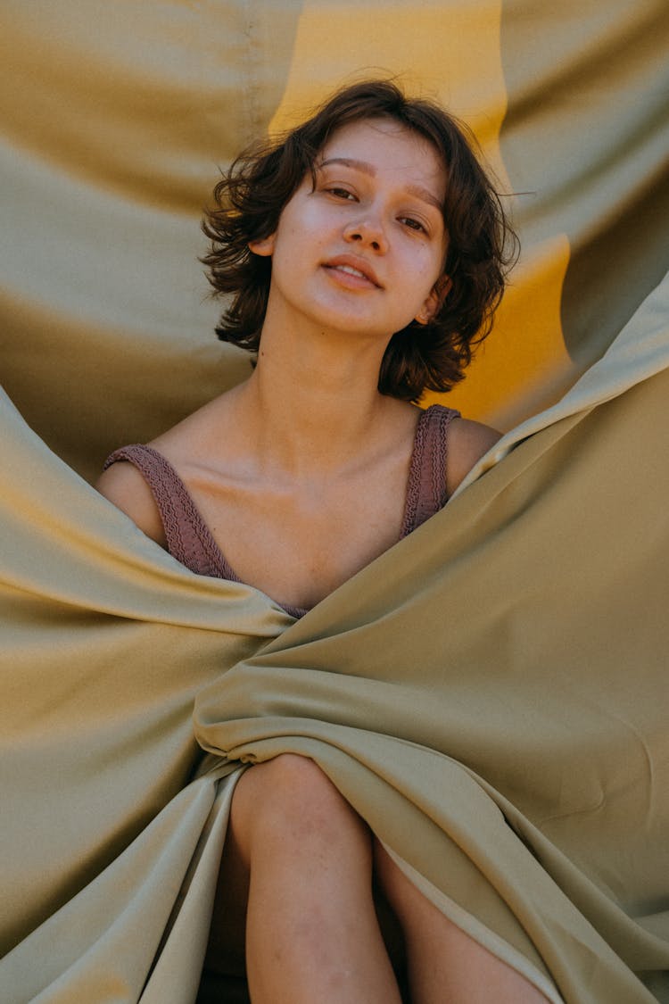 Woman In Sleeveless Top Wrapped In Satin Sheet