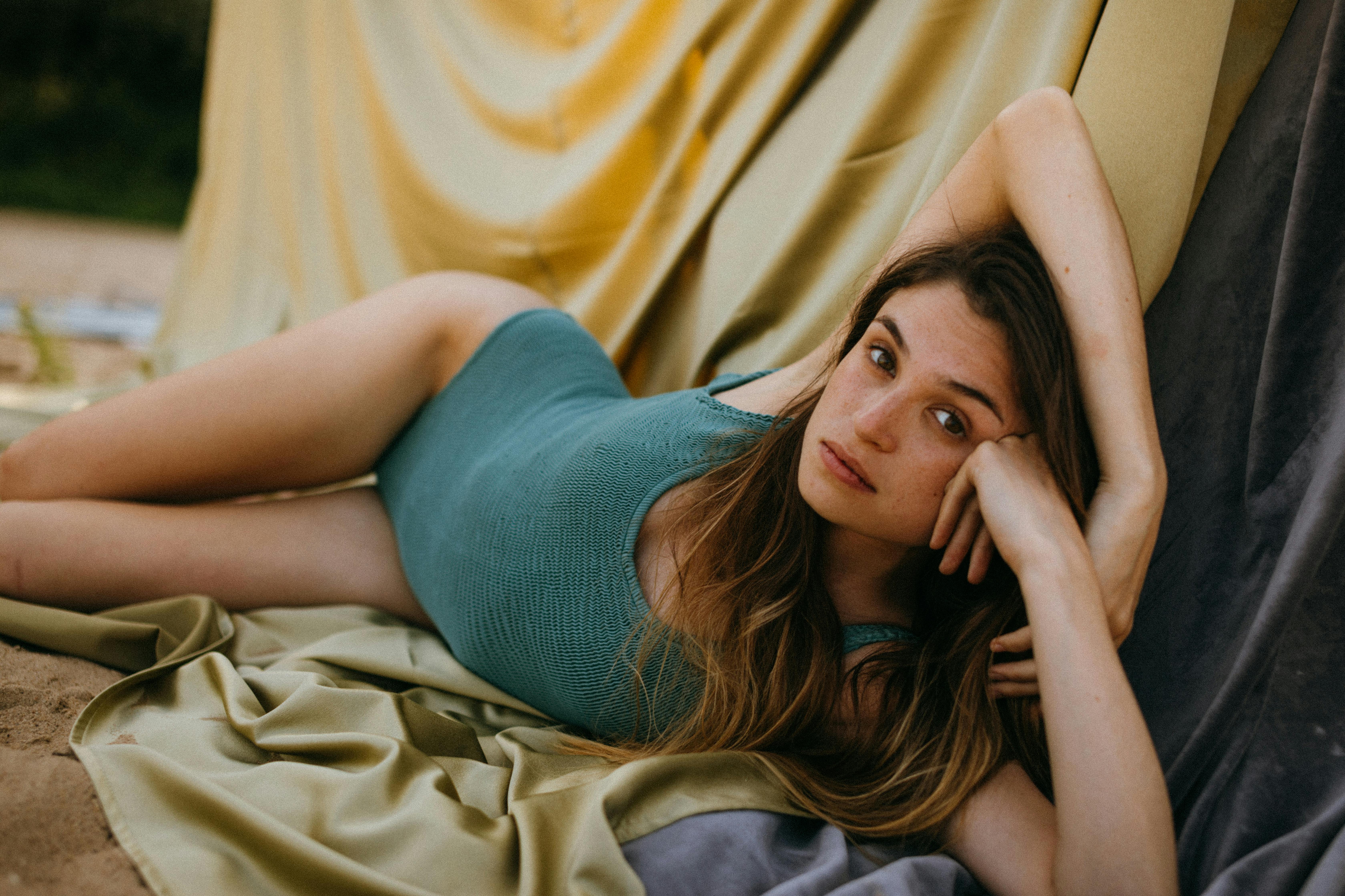 Beautiful woman reclining on soft silk fabrics, relaxed and dreamy in low intimate light