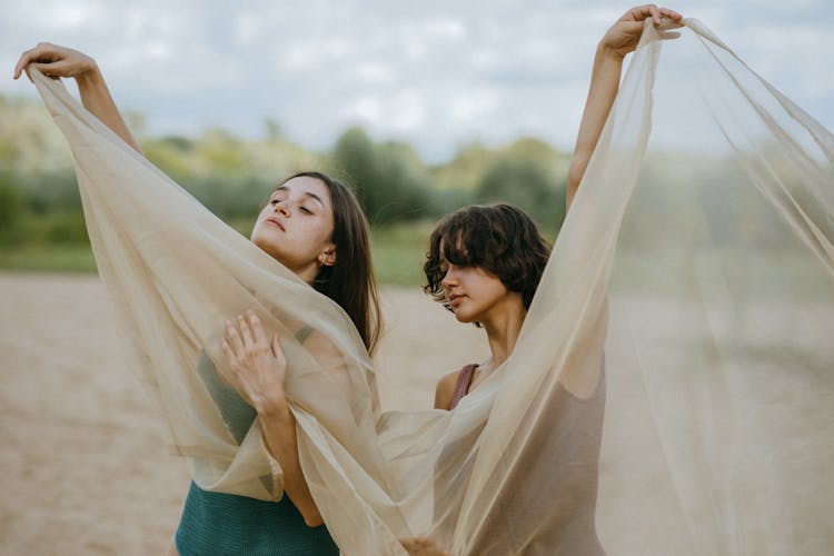 Two Women Posing With Sheer Cloth On Beach