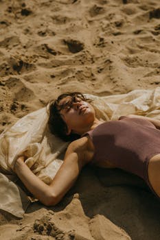 Woman relaxing and sunbathing on a sandy beach in summer, wearing a swimsuit.