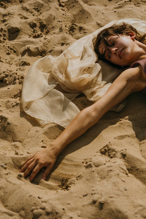 Woman lying on back on sand