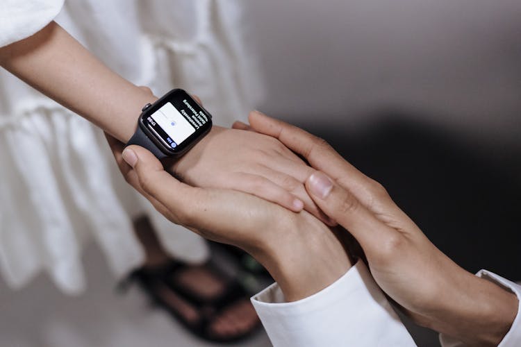 Mother Holding Hand Of Daughter With Smartwatch